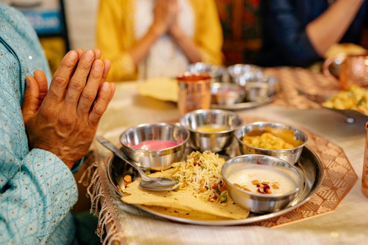 Traditionelle ayurvedische Mahlzeit auf einem Thali mit achtsamem Gebetsritual