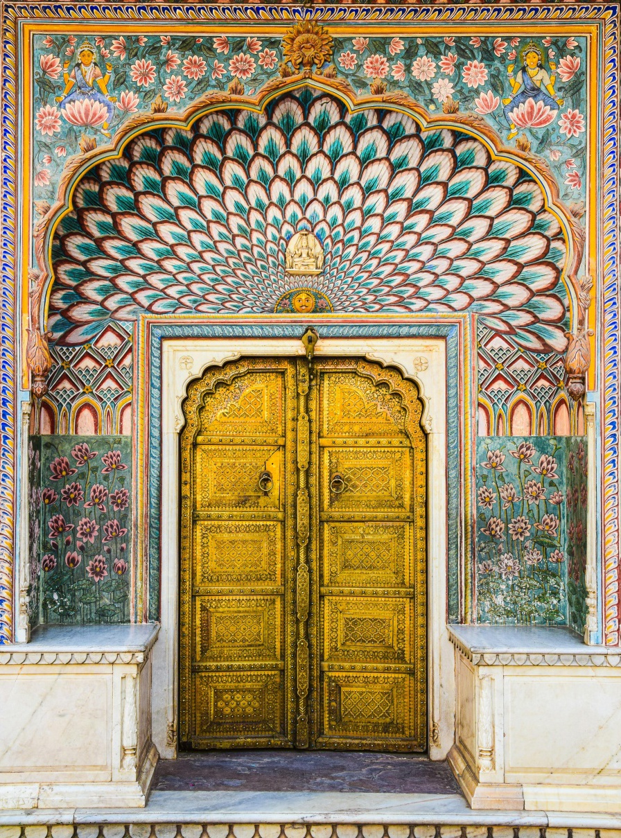 Ornate golden door of the Peacock Gate at City Palace Jaipur, featuring intricate peacock and floral motifs in traditional Rajasthani architecture, India.