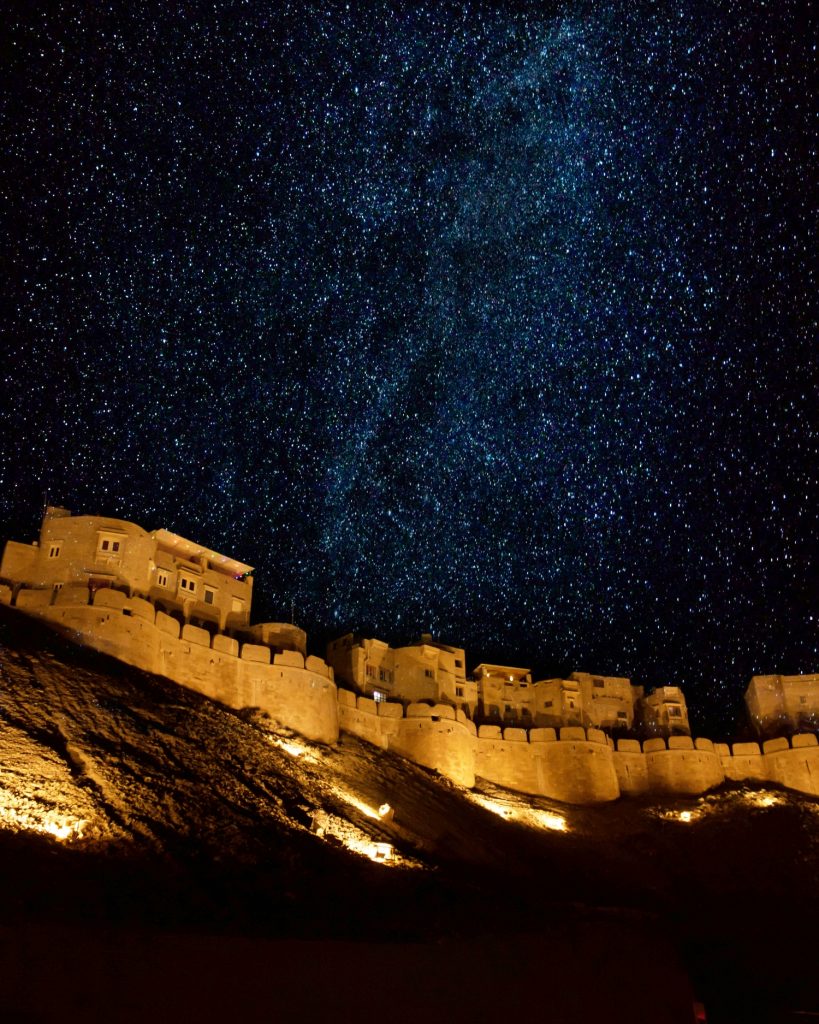 Jaisalmer Fort in Rajasthan illuminated at night under a star-filled desert sky, showcasing India’s historic golden fort.
